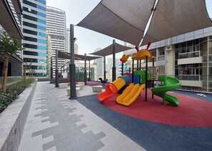 Ein Spielplatz mit Rutschen und Klettergerüsten, umgeben von modernen Gebäuden.