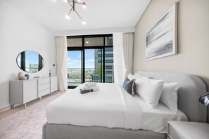 A modern hotel room with a large bed, a bedside table, a mirror, a window with curtains, and a city view. - StayShort - Chic 1 Bedroom Unit in Dubai Marina that Sleeps 4! (Dubai)