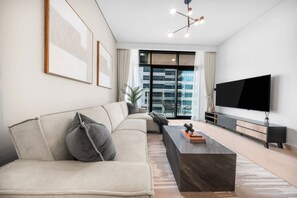 A modern living room with a sofa, a coffee table, and a flat-screen TV. - StayShort - Chic 1 Bedroom Unit in Dubai Marina that Sleeps 4! (Dubai)