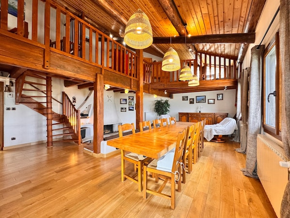 Un comedor amplio con una mesa y sillas de madera, una escalera y vistas al exterior.