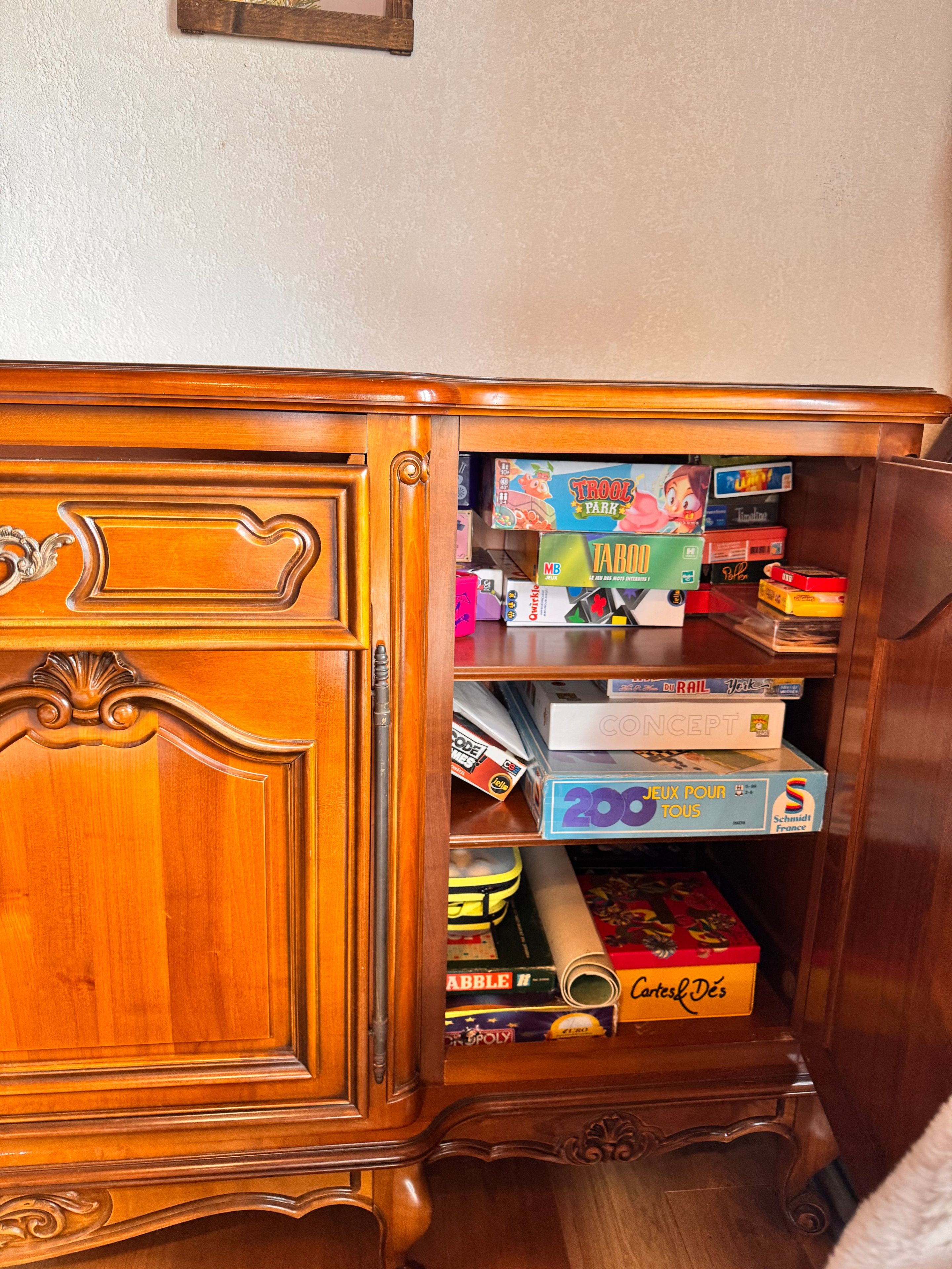 A wooden cabinet with a drawer containing various board games.