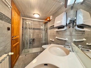 Un baño moderno con ducha, dos lavamanos y zona de ducha con cerramiento de vidrio.