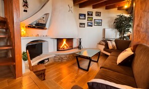 Ein gemütliches Wohnzimmer mit Kamin, Holzmöbeln und einer Wendeltreppe.