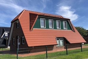 Ein zweistöckiges Haus mit rotem Ziegeldach und grünen Wänden.