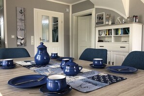 Un coin repas avec une table dressée pour quatre personnes, agrémenté de vaisselle bleue et d’un set de table à motifs.
