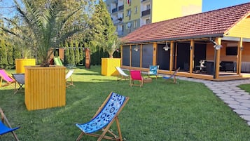 Un espace extérieur résidentiel comprenant une terrasse, des sièges et une aire de jeux.