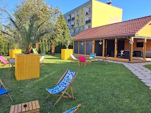 Uma área externa residencial com varanda, assentos e um parquinho.