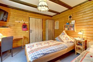 Ein gemütliches Zimmer mit einem hölzernen Bett, einem Schreibtisch, einem Stuhl und einem Bücherregal.