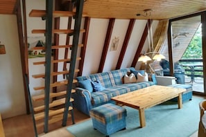 Een gezellige woonkamer met een blauwe bank, een houten salontafel en een ladder tegen de muur.