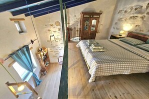 A bedroom with a wooden bed, a wardrobe, a small table, and a hanging light fixture. - Agio Farago Gallery Studio (Pitsidia)