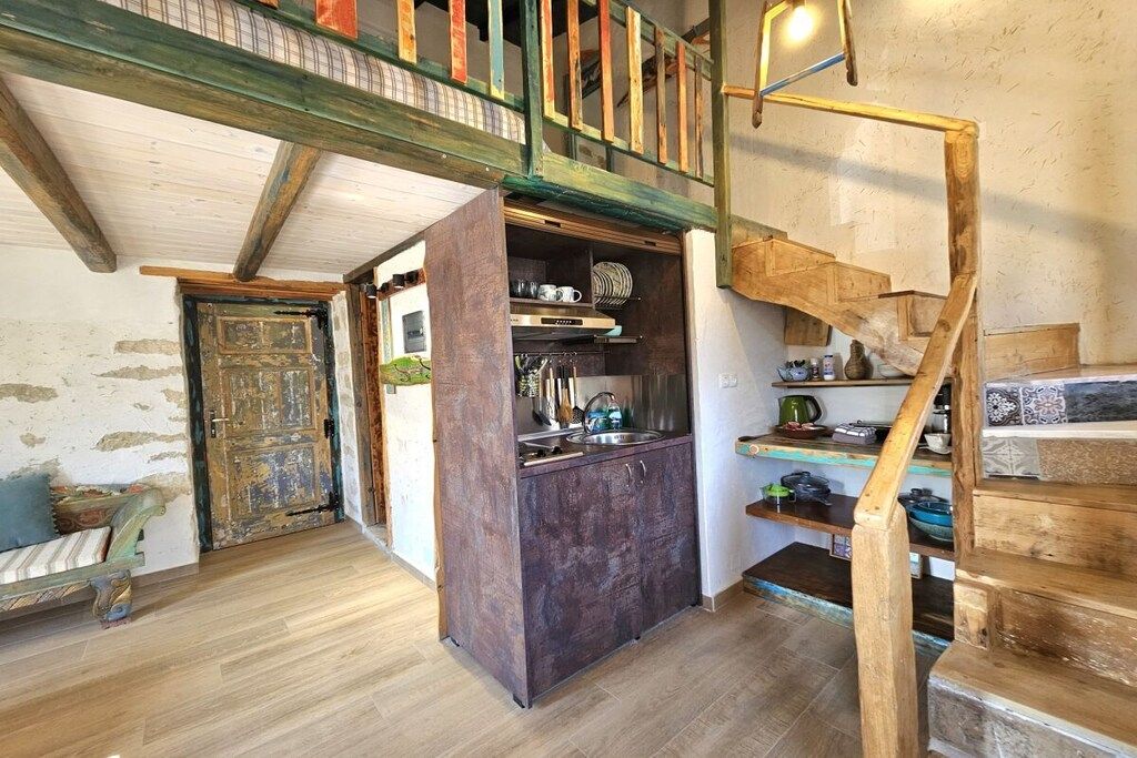 Una cocina rústica con gabinetes de madera, estufa empotrada y una escalera de madera.