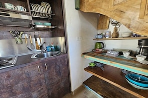 A kitchen with a stainless steel sink, wooden cabinets, and a wooden countertop with various kitchen items. - Agio Farago Gallery Studio (Pitsidia)