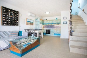 A living room with a glass coffee table, a sofa, a wall-mounted shelf with decorative items, and a staircase leading to the upper floor. - Villa in Pitsidia with swimming pool (Pitsidia)