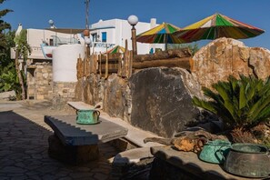 A stone patio with a rustic fence, a stone bench, and a colorful umbrella. - Villa in Pitsidia with swimming pool (Pitsidia)