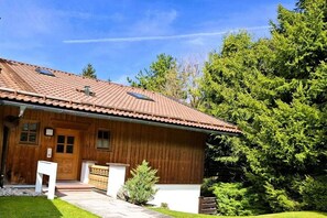 A wooden cabin with a tiled roof, a front door, and a small porch area. - Floor cutting suites "Luxburg" (Tegernsee)