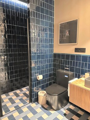 Een badkamer met douche, toilet en wastafel.