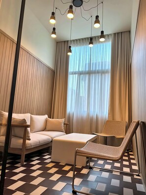 A room with a sofa, a chair, a patterned floor, and a window with curtains. - La Ría Urban Apartments (Bilbao)