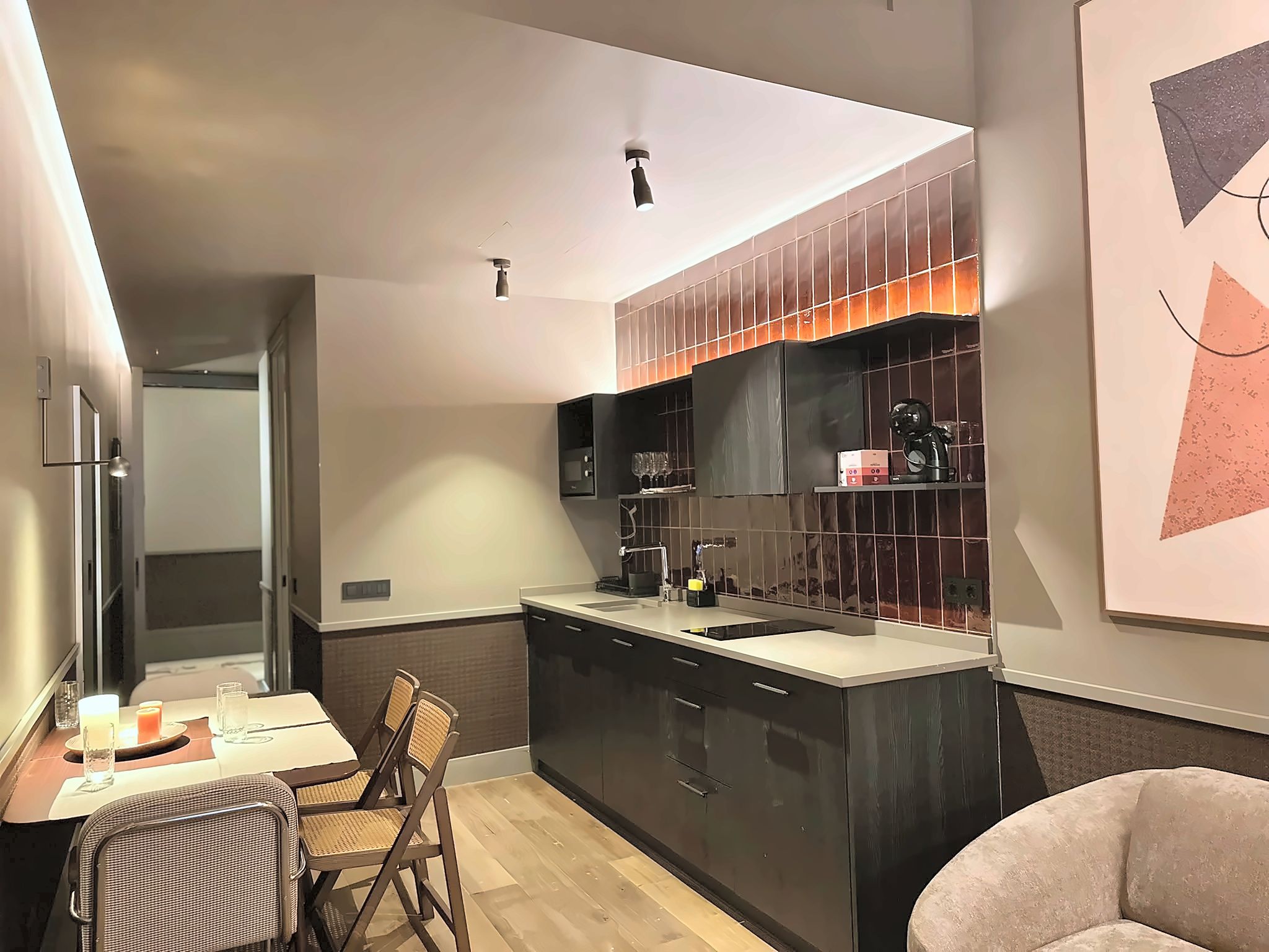 Una cocina moderna con una isla central, muebles oscuros y un comedor con mesa y sillas.
