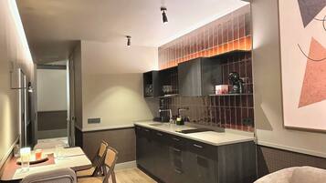 Una cocina moderna con una isla central, muebles oscuros y un comedor con mesa y sillas.