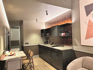 Een moderne keuken met een centraal eiland, donkere kastjes en een eetgedeelte met een tafel en stoelen.