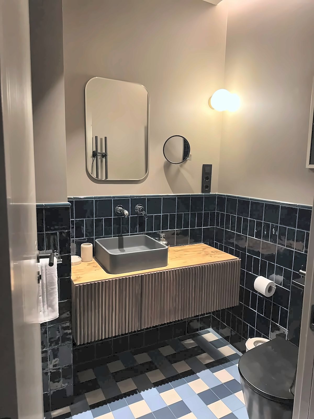 Un baño con un lavamanos rectangular, un espejo, un inodoro y un perchero para toallas.