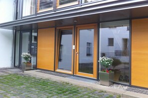 A modern building with large glass doors, a yellow shutter, and potted plants. - Holiday home with 2 bedrooms (Seebad Heringsdorf)