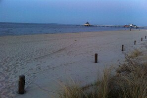 A beach with a pier extending into the water, a small hut, and wooden posts along the shore. - Holiday home with 2 bedrooms (Seebad Heringsdorf)