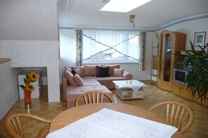 A living room with a sofa, a dining table, and a TV. - Apartment with 3 bedrooms (Afritz am See)
