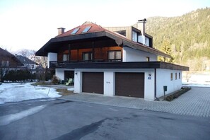 A two-story house with a sloped roof, a balcony, and a garage. - Apartment with 3 bedrooms (Afritz am See)
