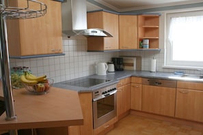 A kitchen with wooden cabinets, a stainless steel oven, a coffee maker, and a fruit bowl. - Apartment with 3 bedrooms (Afritz am See)