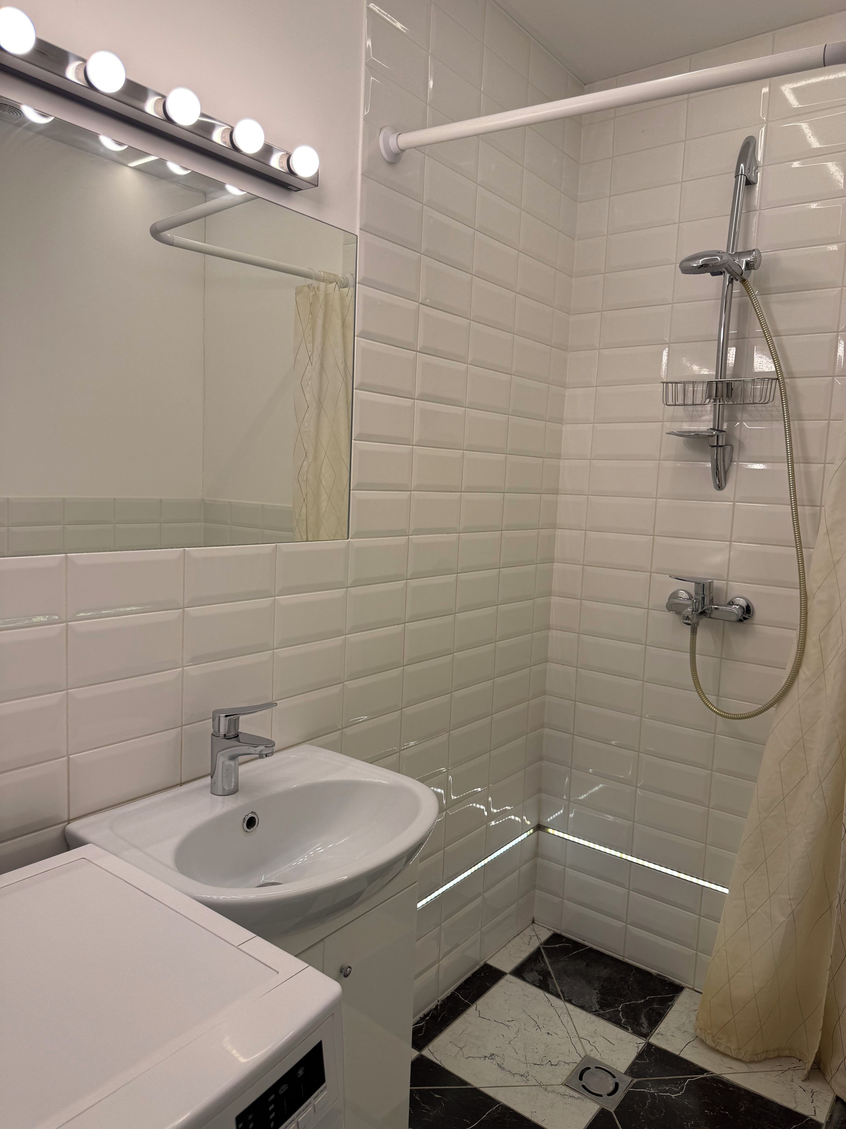Une salle de bain avec un lavabo blanc, un miroir et une douche.