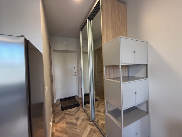 A hallway with a sliding glass door, a white wardrobe, and a herringbone-patterned floor.