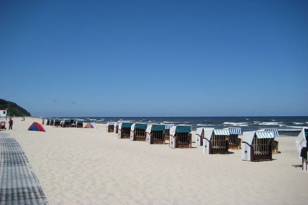 A beach with rows of beach huts and a tent.