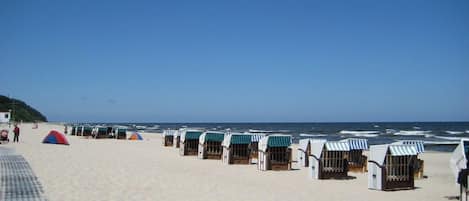 A beach with rows of beach huts and a tent.