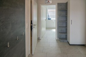 A hallway with a door on the left, a staircase on the right, and a window at the end. - Holiday apartment with 1 bedroom (Bensersiel)