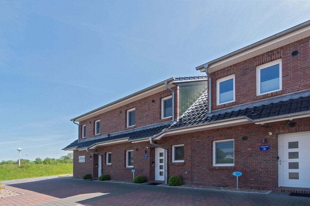 Un bâtiment à deux étages, construit en briques, avec un toit plat, une porte de garage et une allée pavée.