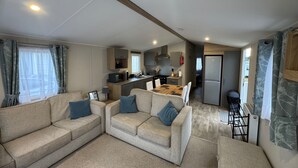 A compact living space with a sofa set, a kitchen area, and a refrigerator. - 2-bed - Sleeps 4 - Free Parking (Sandown)