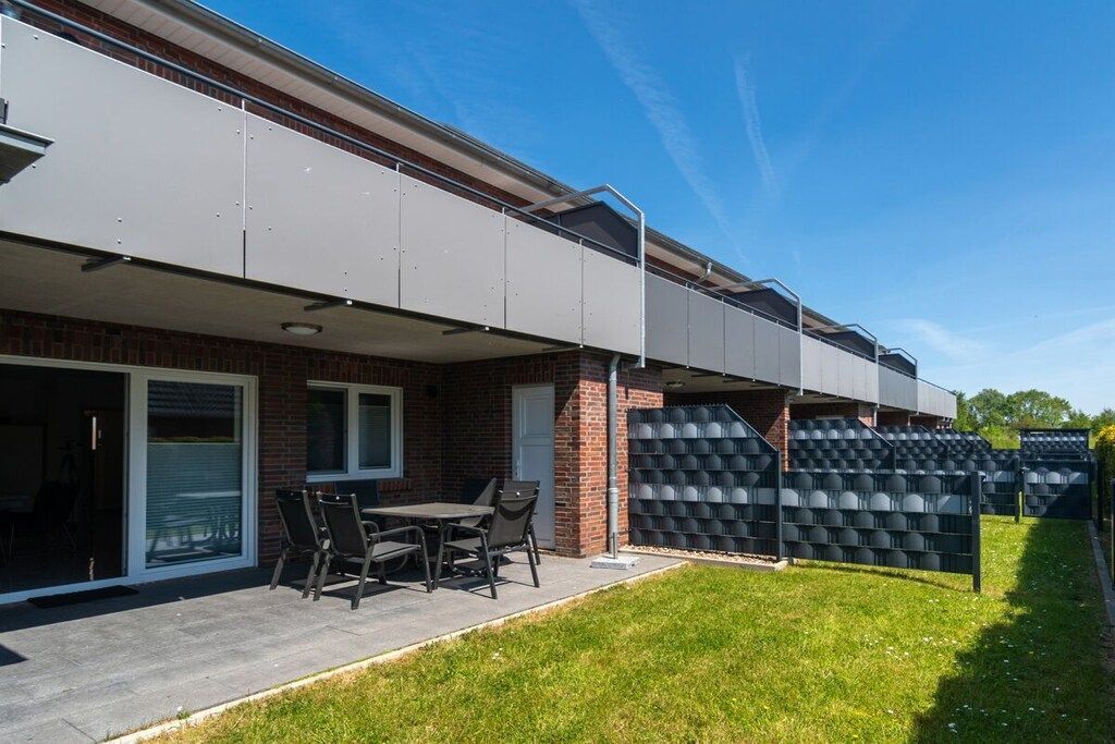 Un immeuble résidentiel doté d’un patio couvert, d’une façade en briques et d’un espace aménagé pour s’asseoir.