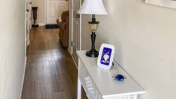 A hallway with a white wicker console table, a lamp, and framed artwork on the walls.