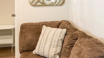 Un divano marrone con un cuscino a righe in una stanza con una parete bianca e uno specchio decorativo.