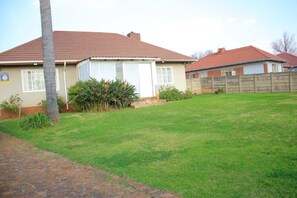 A residential house with a red-tiled roof, a brick pathway, and a grassy yard.