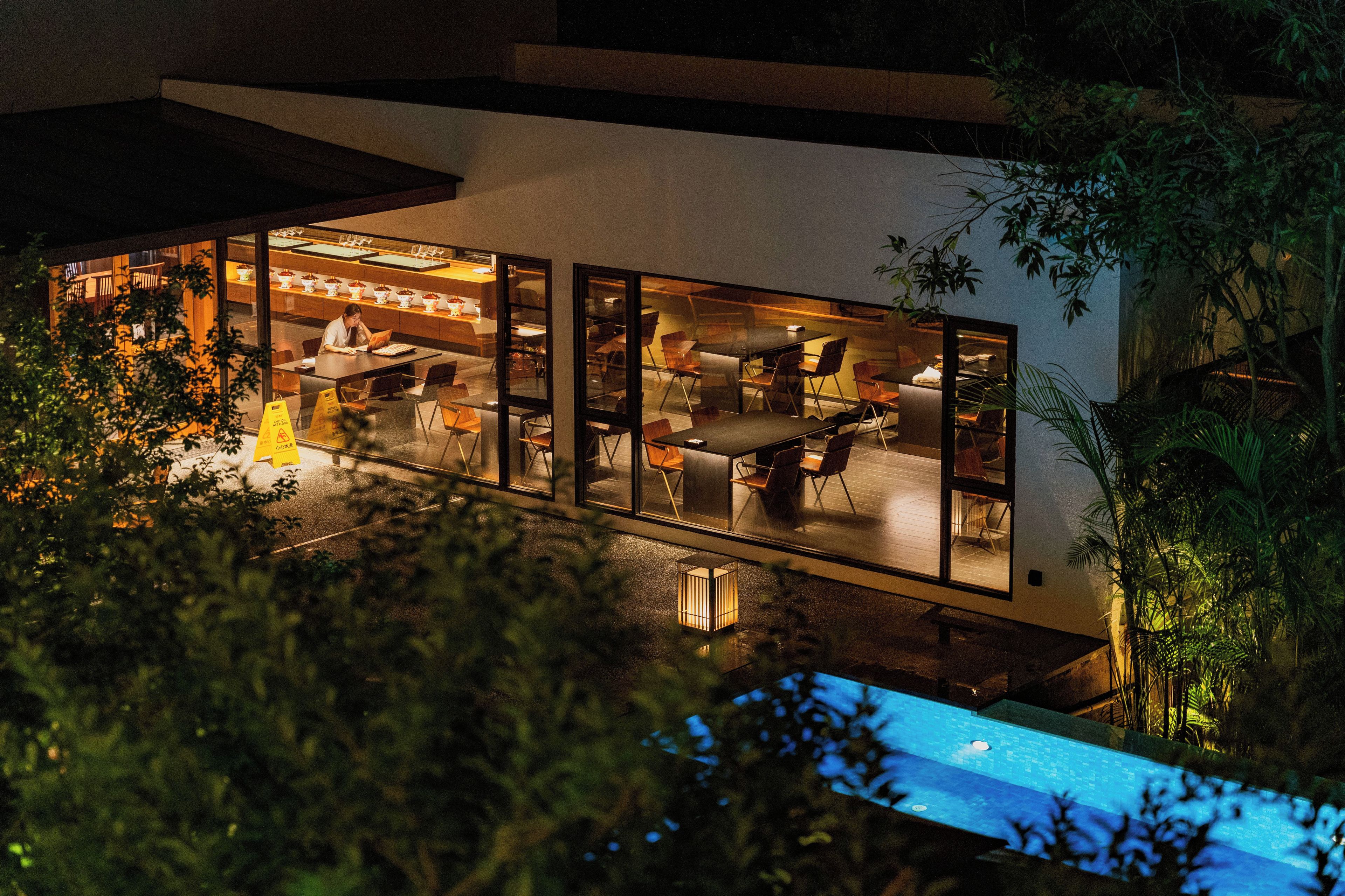Ein modernes Haus mit Glasfassade, Sitzgelegenheiten im Freien und einem Swimmingpool.