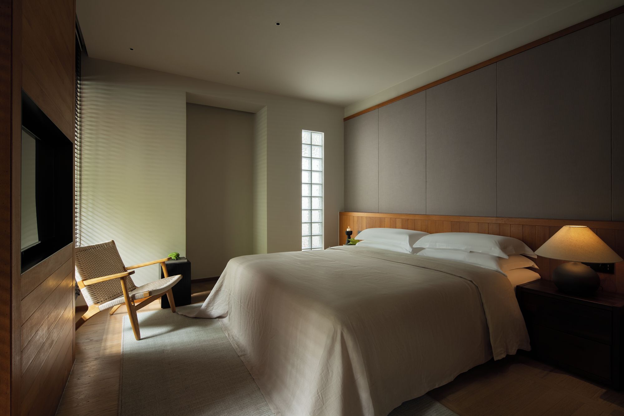 Una habitación de hotel con una cama grande, una silla, una mesita de noche y una ventana.