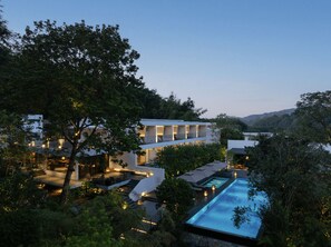 A modern hotel with a swimming pool, outdoor seating, and a view of the surrounding hills. - SAINT LANCY HOTEL (Guangzhou)