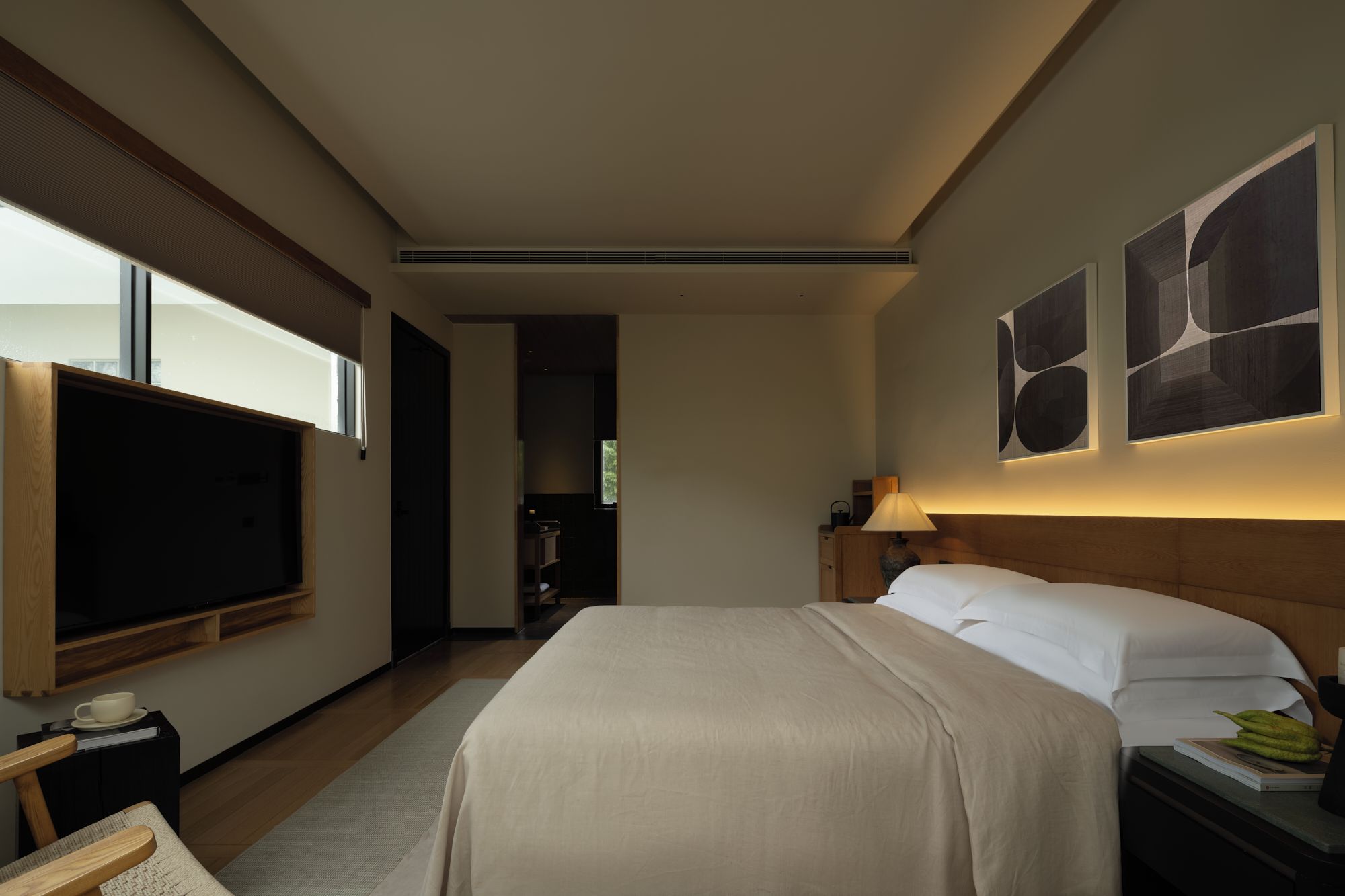 Habitación de hotel con cama, televisión de pantalla plana, mesita de noche y una obra de arte en la pared.