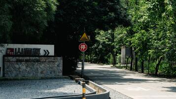 Una carretera con una señal de pare y una señal de advertencia triangular. Hay un muro de piedra con un letrero que dice 'Suan Anxi'.