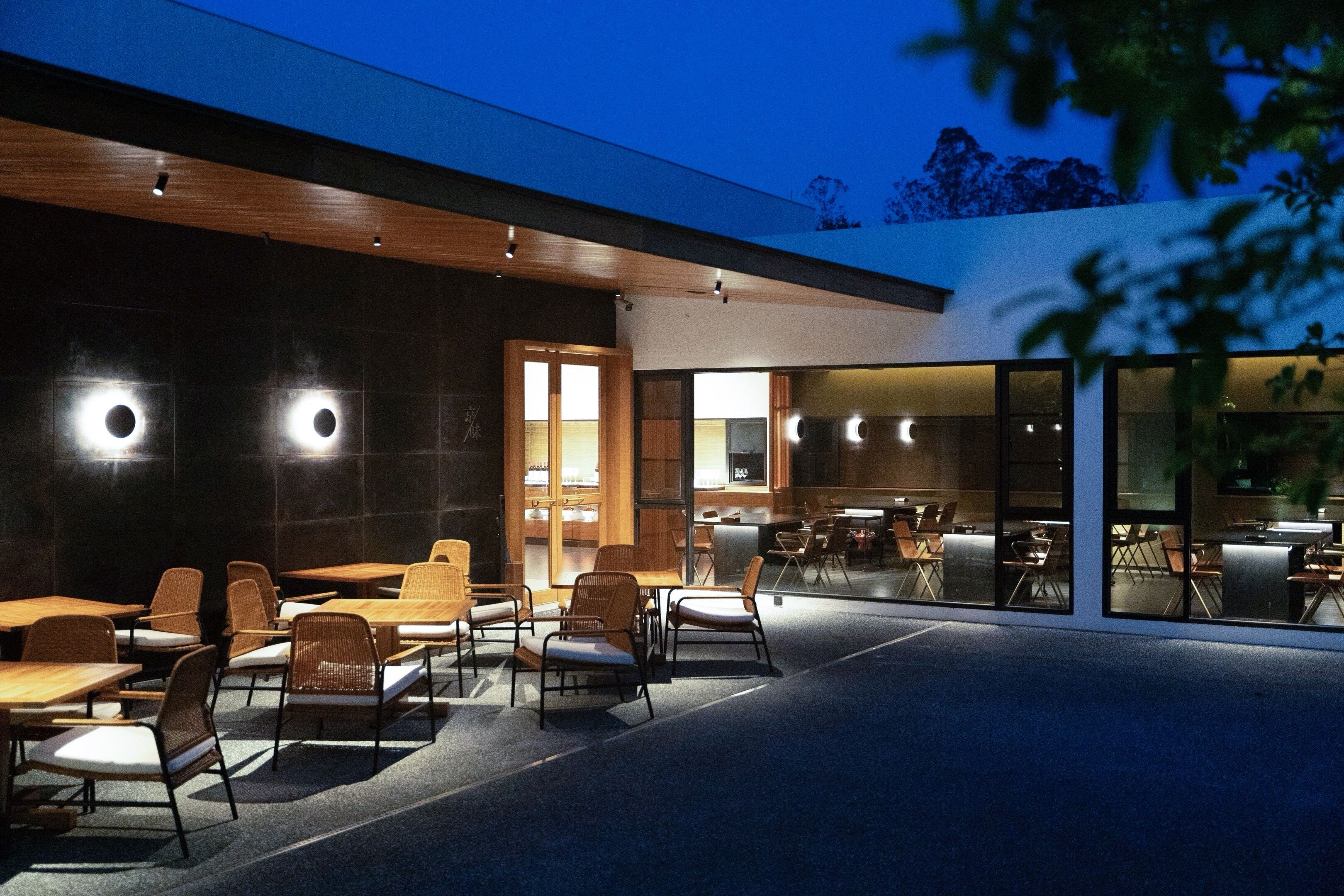 Un espace extérieur aménagé avec des tables et des chaises, un plafond en bois et un mur en verre.