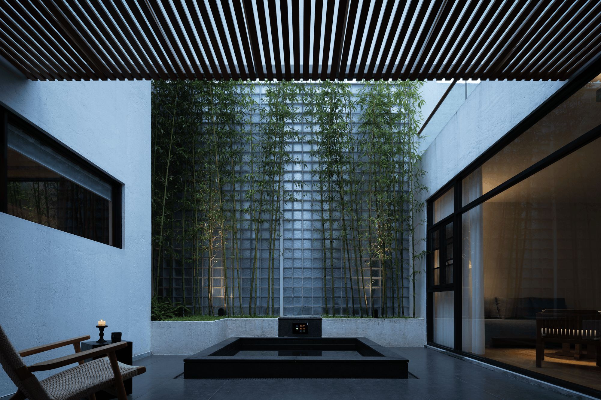 Un intérieur moderne au design minimaliste, comprenant un espace salon, un mur recouvert de bambou vertical et une horloge numérique.