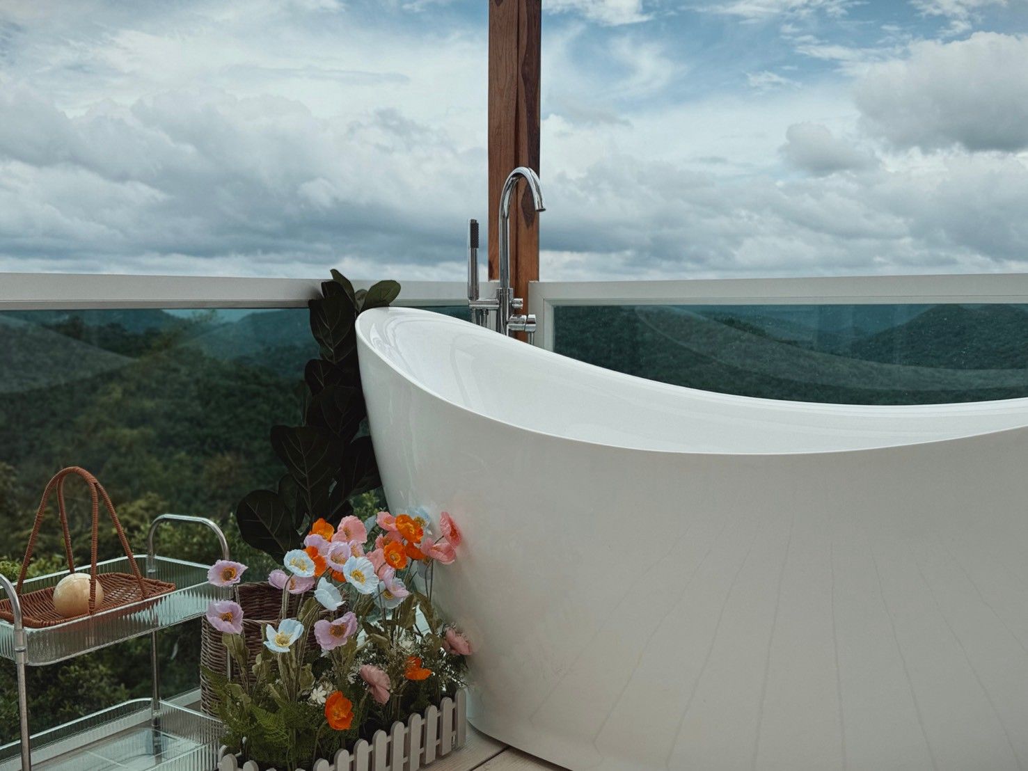A modern bathroom with a freestanding bathtub, a glass shower enclosure, and a view of a mountainous landscape.