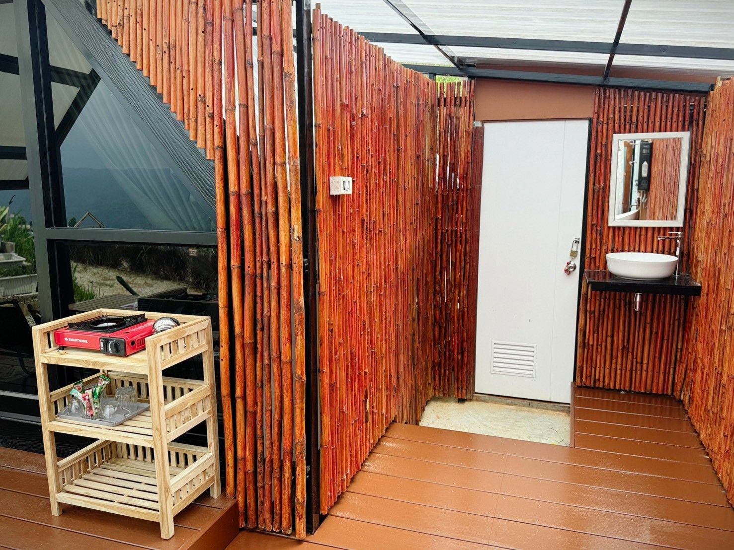 Un baño con pared de madera, una puerta blanca y un lavamanos con espejo.